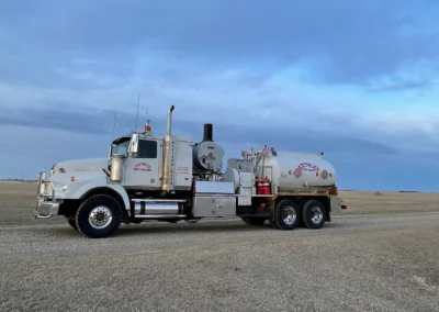 Hot oiler truck parked on a dirt site in an oilfield with equipment attached.
